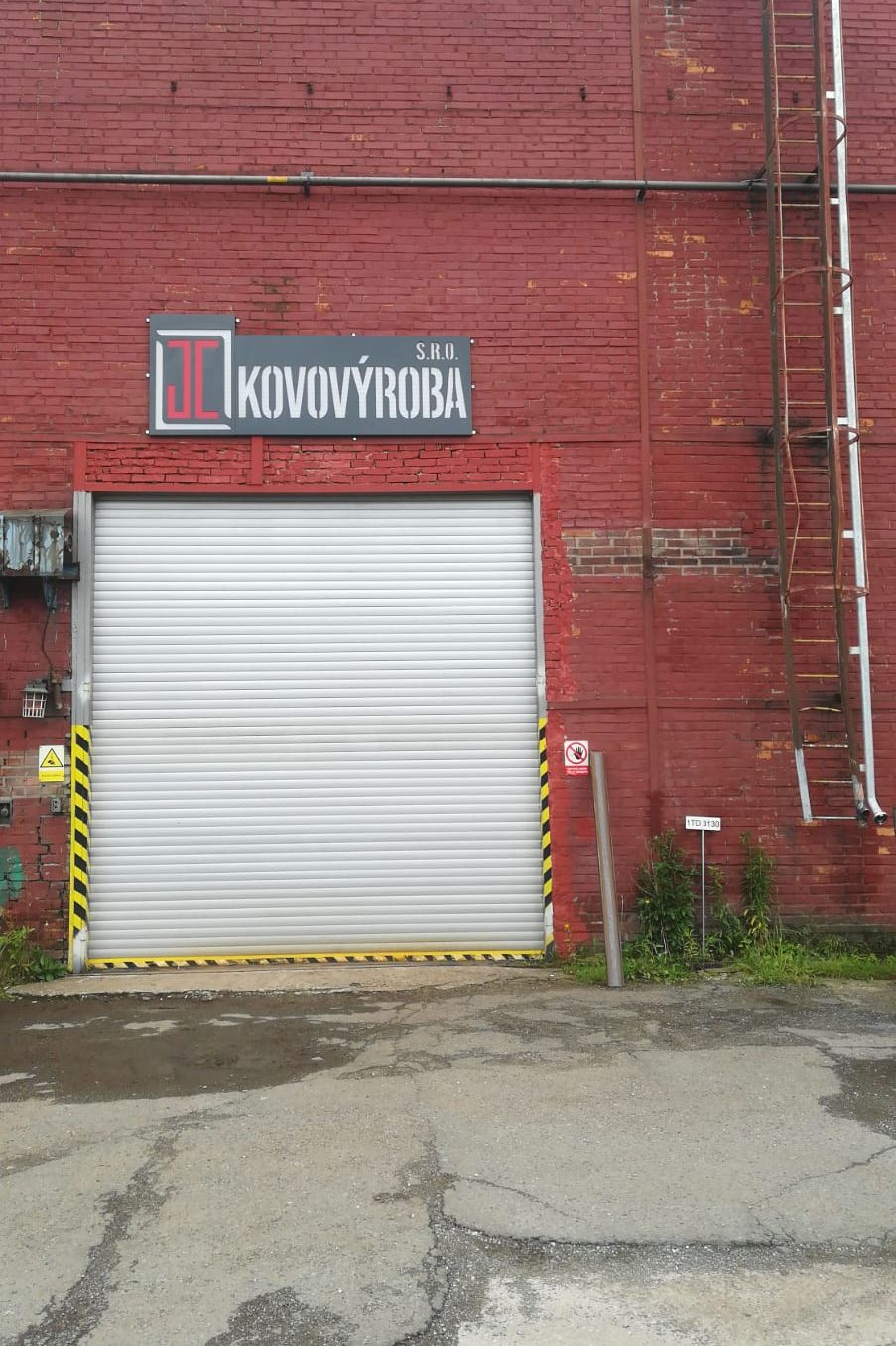 Nové logo nad bránou vedoucí do dílny